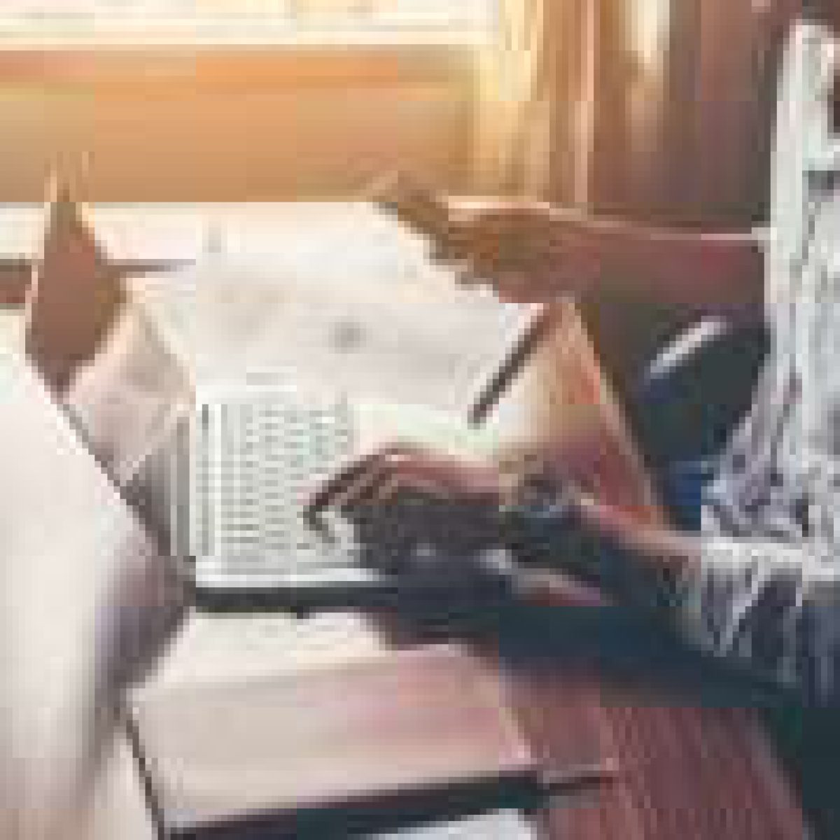 Businessman hands using cell phone with laptop at office desk.